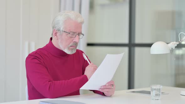 Old Man Reading Documents in Office