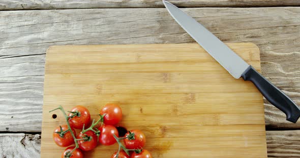 Cherry tomatoes and kitchen knife on chopping board