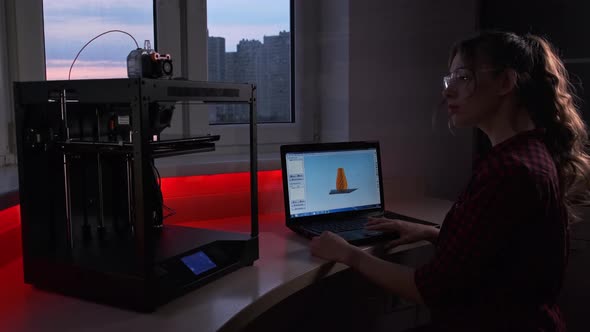 Creative Female Designer Pushing Button on Control Panel of 3d Printer to Start It While Sitting in