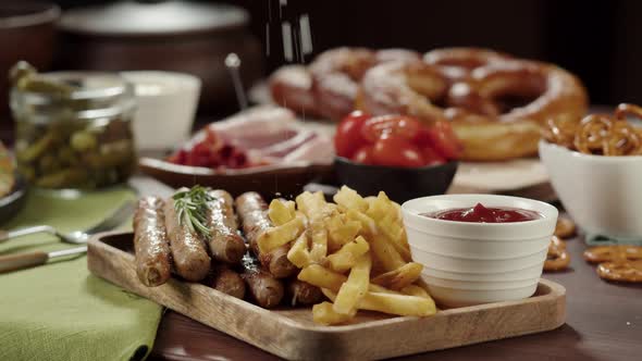 Sprinkling Sault on Smoked Sausages and French Fries Closeup