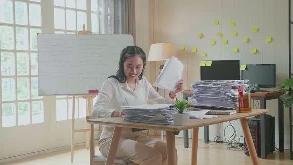 Smiling Asian Woman Enjoys Working With Documents At The Office