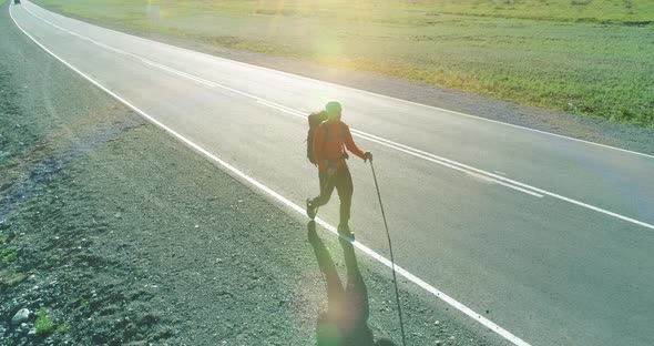 Flight Over Hitchhiker Tourist Walking on Asphalt Road. Huge Rural Valley at Summer Day. Backpack