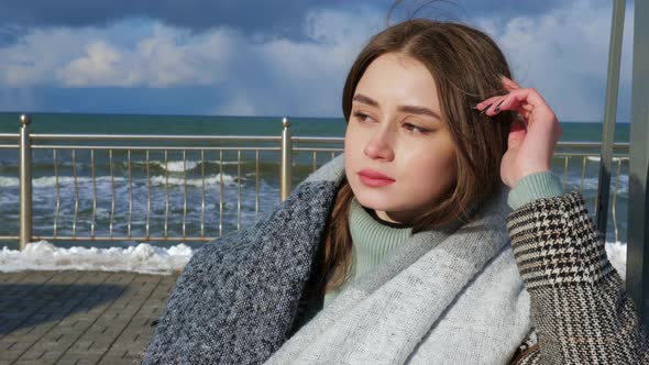 A Woman Wearing a Coat is Sitting on a Swing on the Promenade