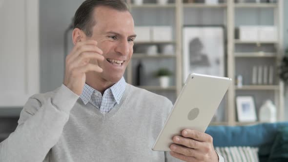 Man Celebrating Success While Using Tablet