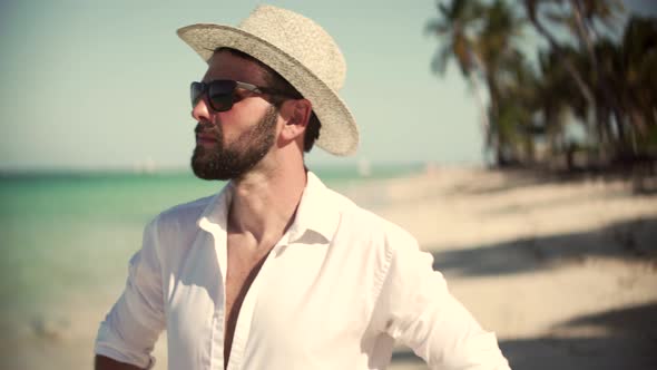 Man Walking On Tropical Beach. Guy Relaxing On Caribbean Beach. Beautiful Tanned Man In Hat.