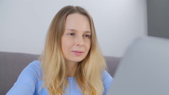 Smiling female doing freelance work on modern laptop computer in living room during lockdown