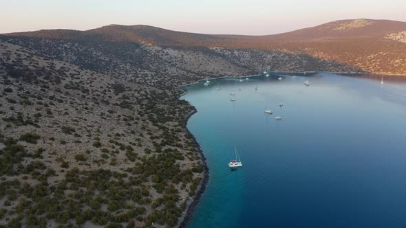 Catamaran and Sail Yachts Anchored at Bay on Deep Blue Sea Water on Sunrise