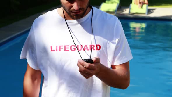 Lifeguard looking at stopwatch near the poolside