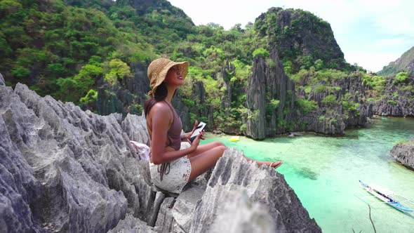 Woman Sitting On Limestone Rocks Holding Smartphone