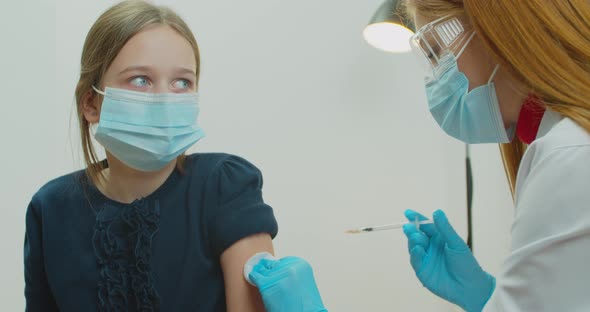 American Doctor Wearing Face Mask Injects a Covid19 Vaccine Into the Girl Shoulder at Home