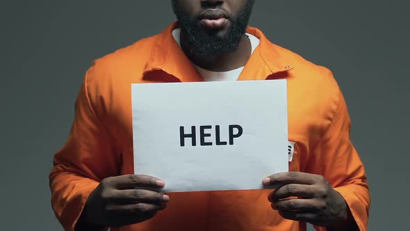 Help Word on Cardboard in Hands of Afro-American Prisoner