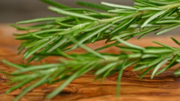 Super Slow Motion Shot of Fresh Rosemary Falling on Wooden Cutting Board at 1000Fps.