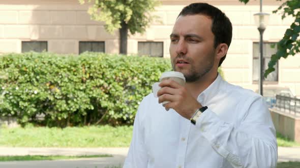 Business Man Drinking Coffee Outdoors in Park