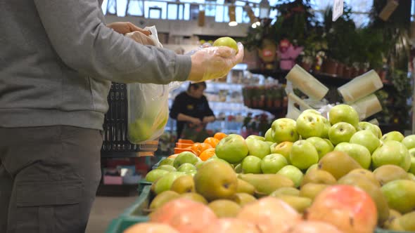 Male Hands Selecting Fresh Apples in Produce Department of Grocery Store and Putting It in Plastic