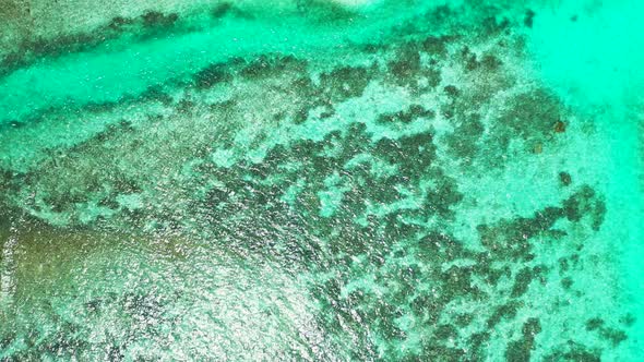 Tropical birds eye travel shot of a white sandy paradise beach and blue water background in 4K