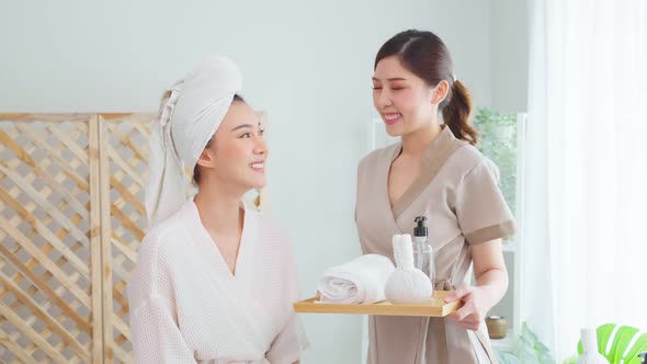 Portrait of Asian young masseuse woman and client looking at camera.