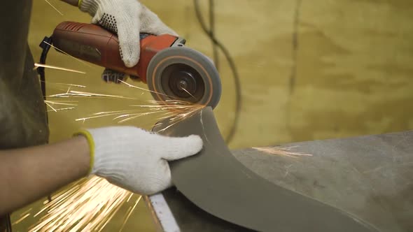 Metal works done by male hands with gloves, power tools and sparks.
