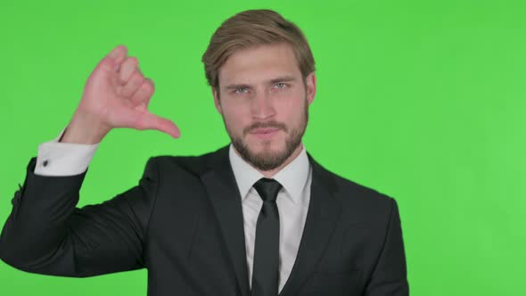 Thumbs Down By Young Businessman on Green Background