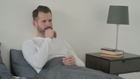 Man Thinking While Sitting in Bed