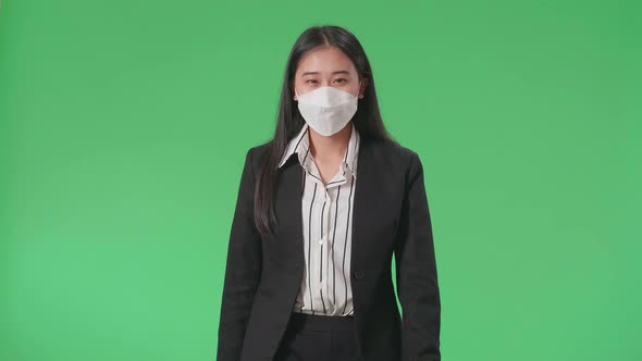 An Asian Business Woman Wearing Mask Walking In Front Of Green Screen In The Studio