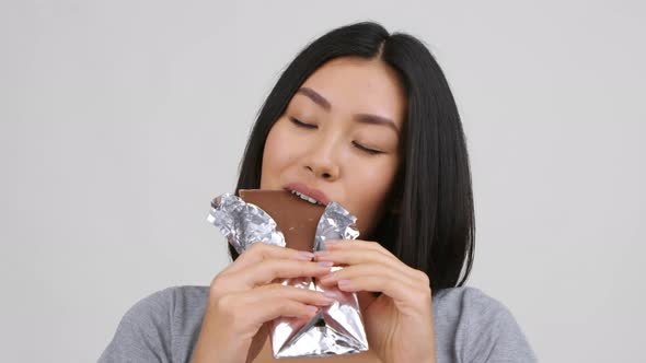 Happy Chinese Female Eating Big Chocolate Posing Over White Background