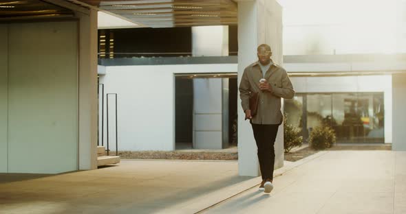 AfricanAmerican Man Drinks Coffee While Walking Around Business Center of City