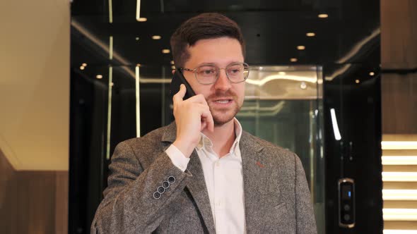 Smiling Business Man It Programmer Talking on Cell Phone in Modern Hallway