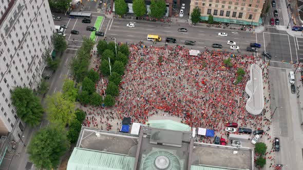 Huge crowd of Native protesters assemble below, pan orbit aerial from high above