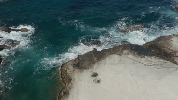 Aerial Birds Eye View of Ocean Waves Crashing on White Rocks in Greece