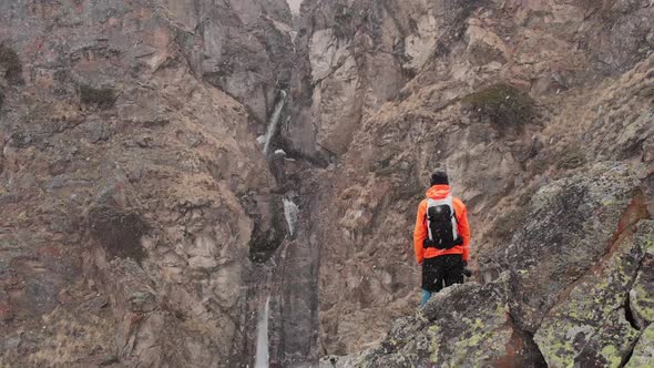 Aerial View of a Young Male Photographer with a Camera in His Hands Stands on a High Rock in a Gorge