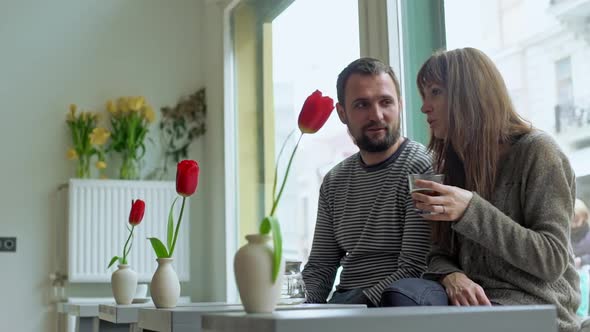 Couple are Talking and Drinking Coffee in Coffeeshop