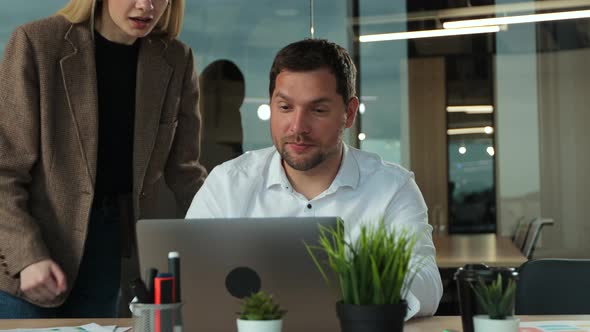 Young Businessman Working on Laptop at Desk in Modern Open Plan Start Up Office Being Joined By