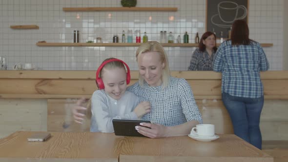 Happy Woman with Daughter Making Video Call in Cafe