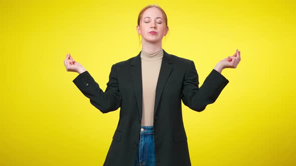 Portrait of Confident Slim Businesswoman in Suit Meditating in Lotus Pose at Yellow Background
