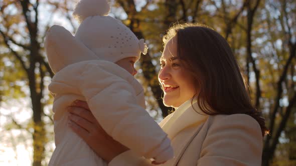 Joyful mom kisses her baby in the park