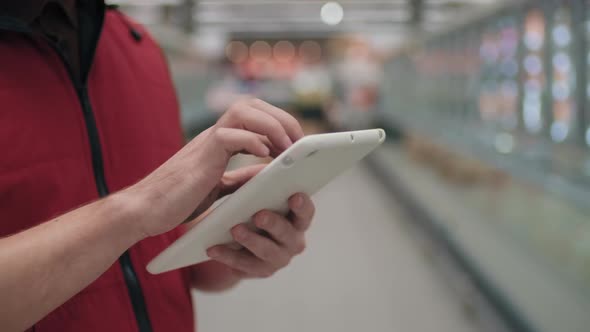 Supermarket Worker Typing On Tablet