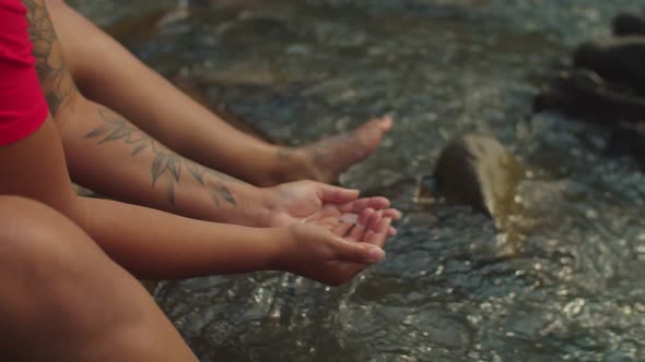 Lovely Black Female Traveler Scooping Up Handful of Water From Mountain Stream and Drinking