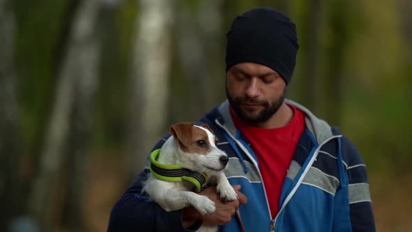 Walk of Dog Owner and Jack Russell Puppy in Autumn Forest, Man Is Holding Animal on Hands and