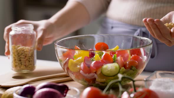 Woman Cooking Vegetable Salad with Pine Nuts