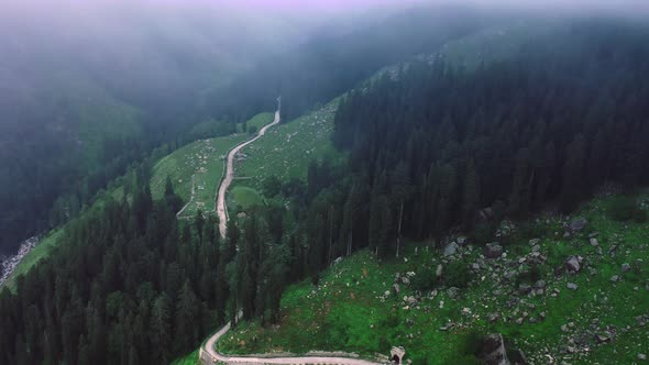 Aerial Shot of a Road Diverging Into the Mountains During Monsoon Framed By Clouds in Manali