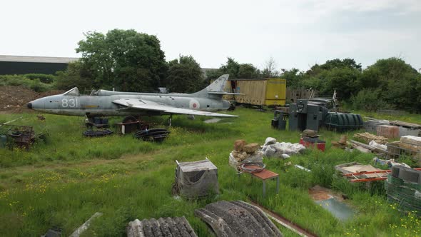 Junk yard British field with discarded Hawker hunter fighter jet side low aerial view