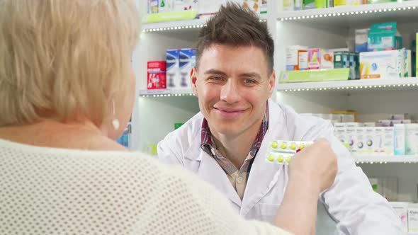 Cheerful Pharmacist Selling Medication To Senior Customer