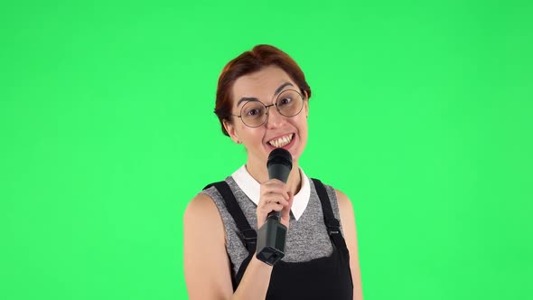 Portrait of Funny Girl in Round Glasses Is Singing Into a Microphone and Moving To the Beat of Music