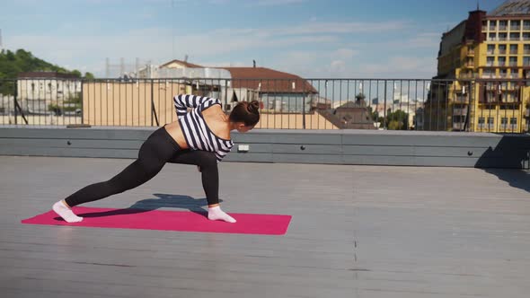 Woman Doing Yoga Exercises on House Roof in Early Morning