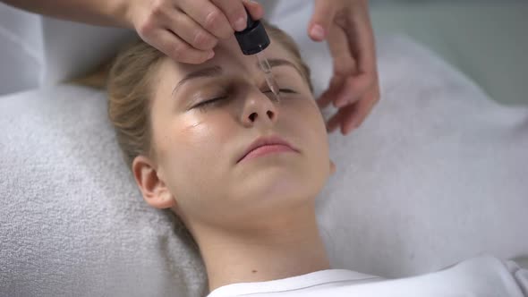 Cosmetologist Moisturizing Skin Under Eyes of Client, Massaging Face Skin