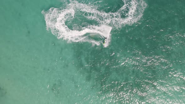 Aerial top view of jet ski or boat drawing a shape on sea ocean turquoise water. Adventure