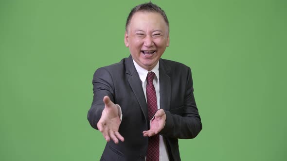 Mature Sketchy Japanese Businessman Giving Handshake Against Green Background