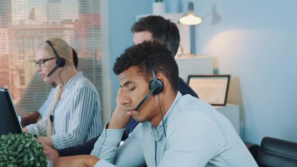 Bored Multiethnic Customer Support Operator Waiting for Telephone Call From Client.