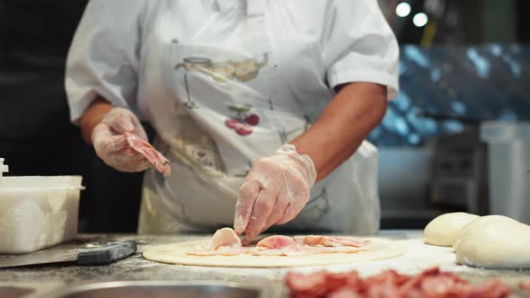 The Pizza Chef Iola Prepares The Pizza Dough For Baking The Chef Puts The Meat On The Prepared Round