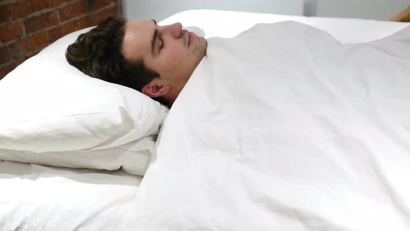 Young Man Falling Asleep in Bed at Night